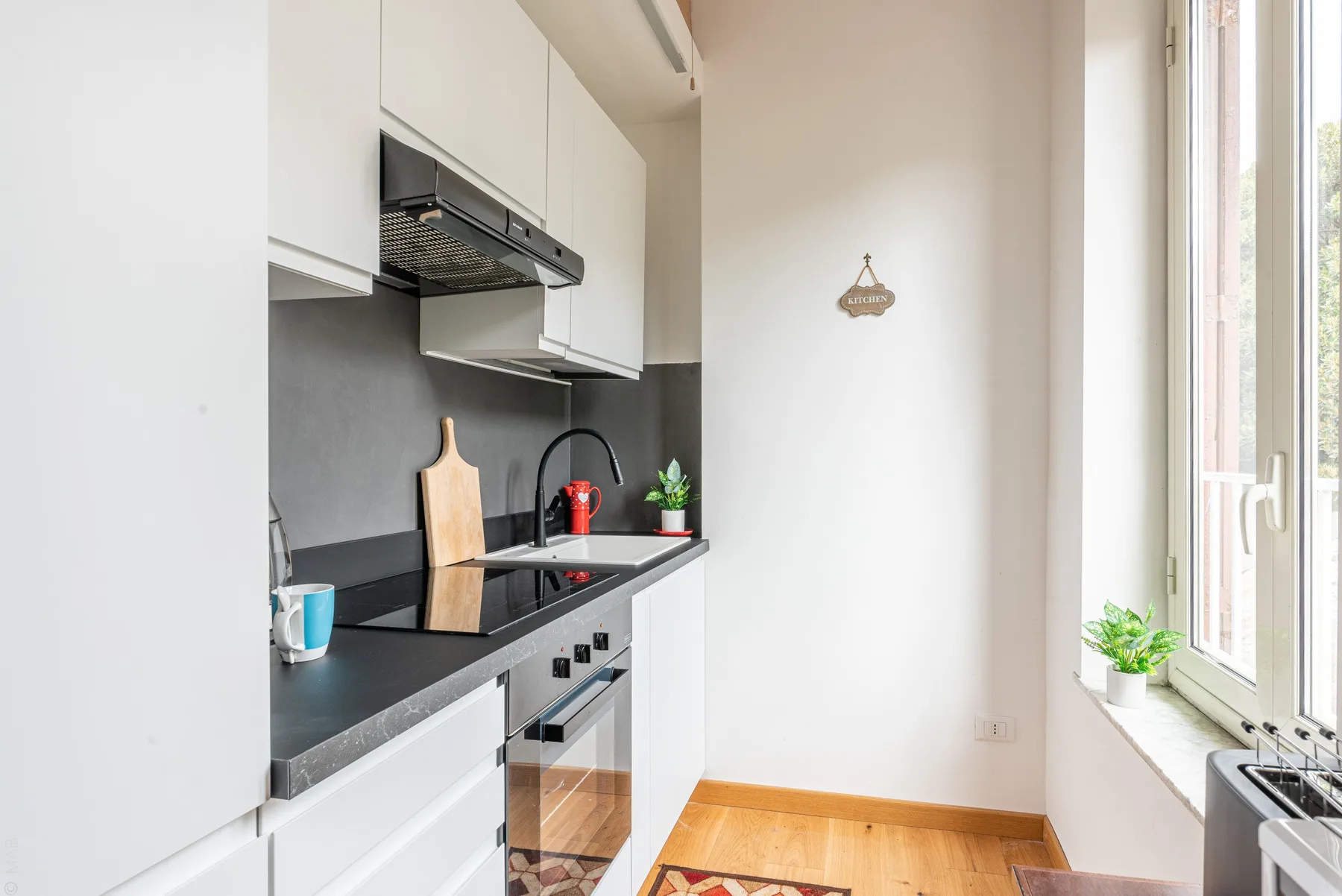 Una cocina compacta con una encimera oscura y una ventana luminosa.