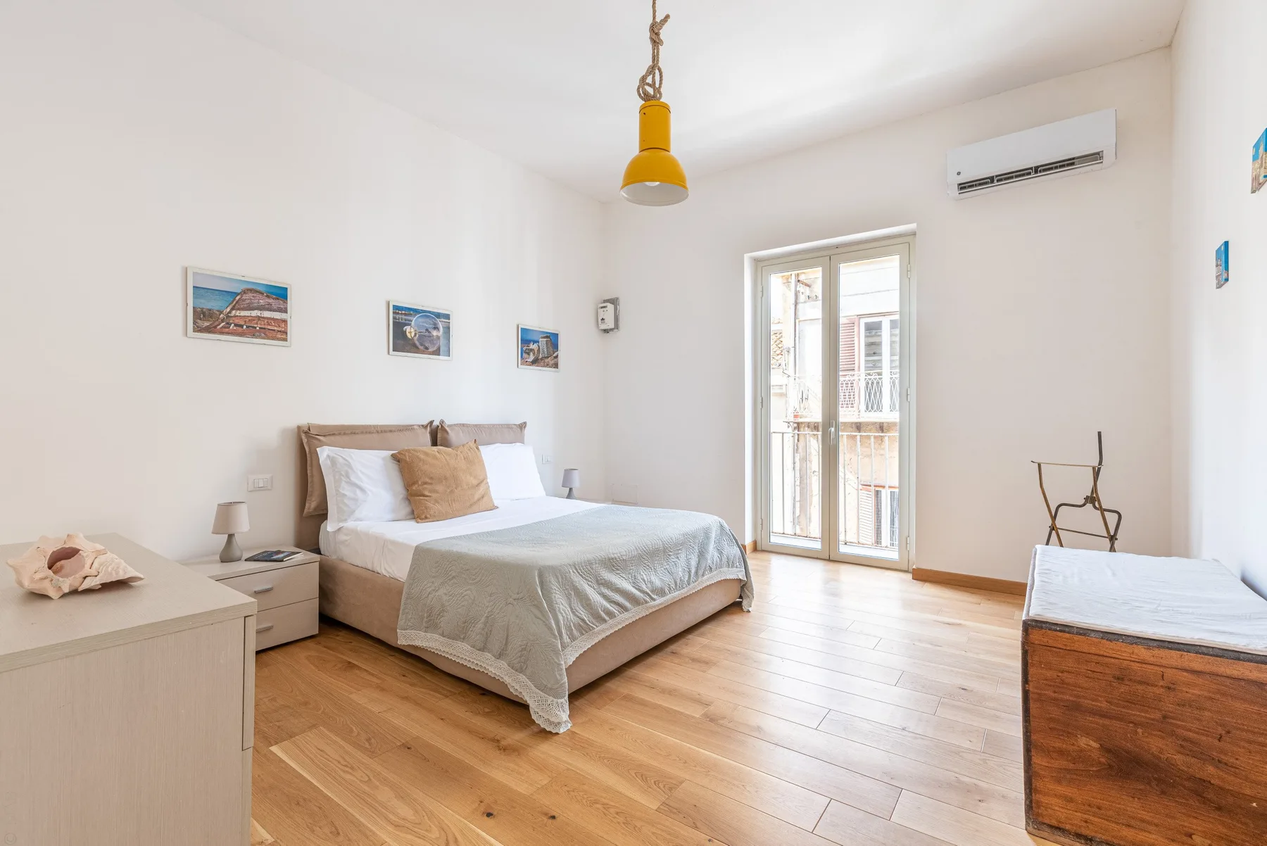 Un dormitorio luminoso con una cama doble y una puerta de cristal al balcón.