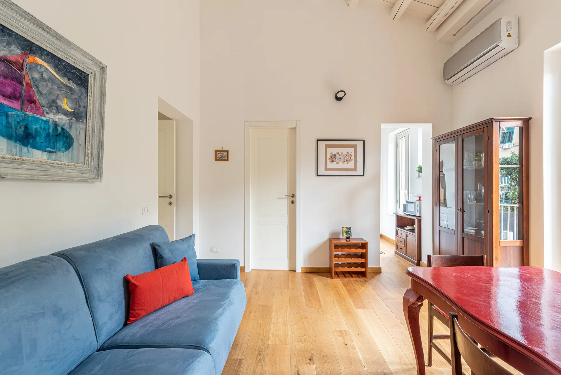 Una luminosa sala de estar y comedor con asientos azules y una mesa de madera.