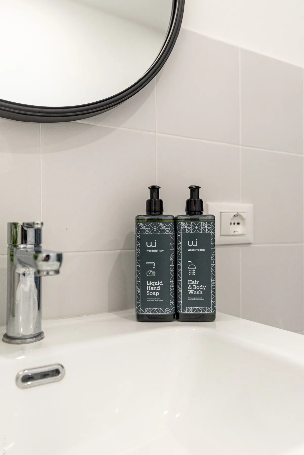 Un lavabo de baño con un grifo cromado y dos botellas oscuras con dispensador.