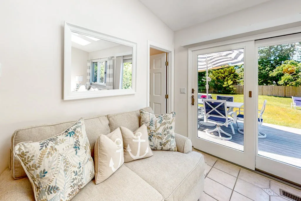 A bright living room with a light-colored sofa beside glass doors opening onto a patio.