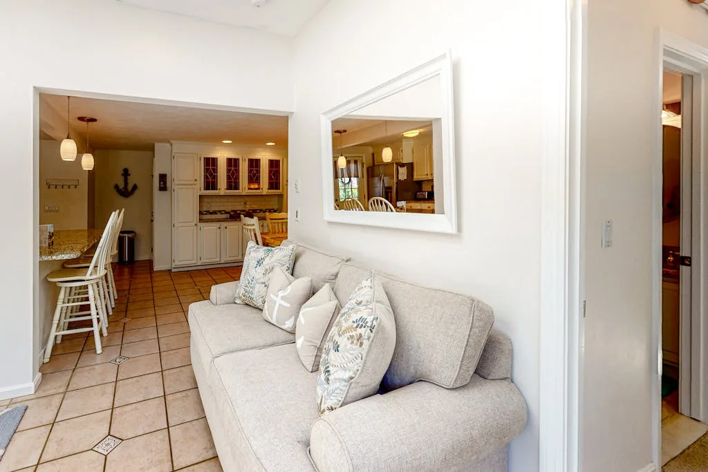 A bright living area with a light-colored sofa beside a tiled dining space.