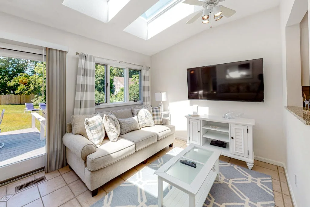 A bright living room with a sofa and a wall-mounted television.