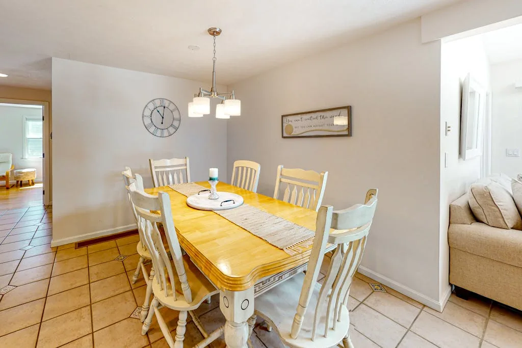A dining area with a wooden table and chairs beneath a hanging light.