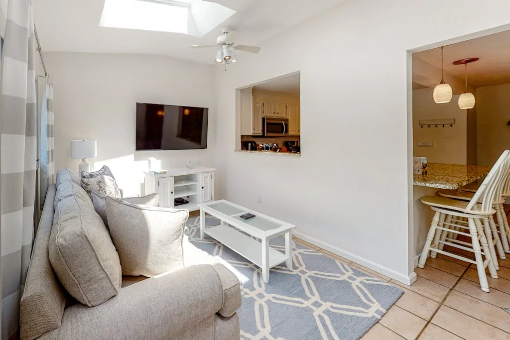 A bright living room with seating, a television, and a coffee table.