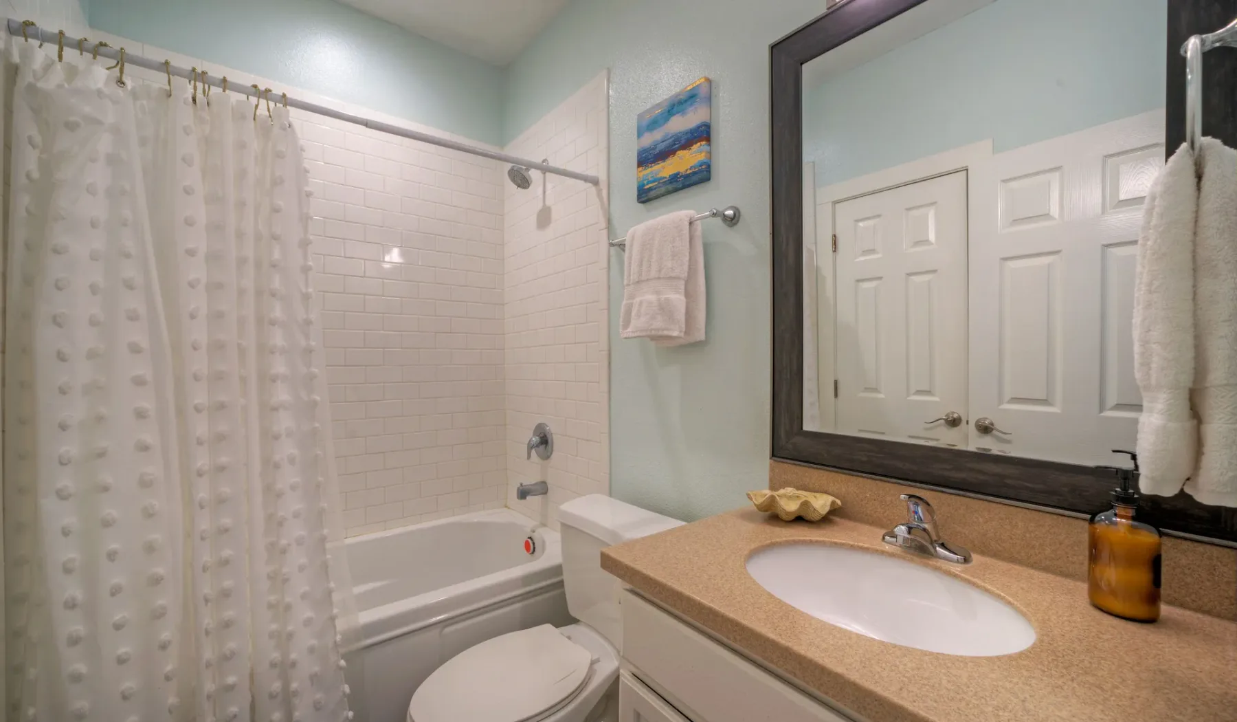 Un baño con bañera, cortina de ducha, inodoro y lavabo con tocador.