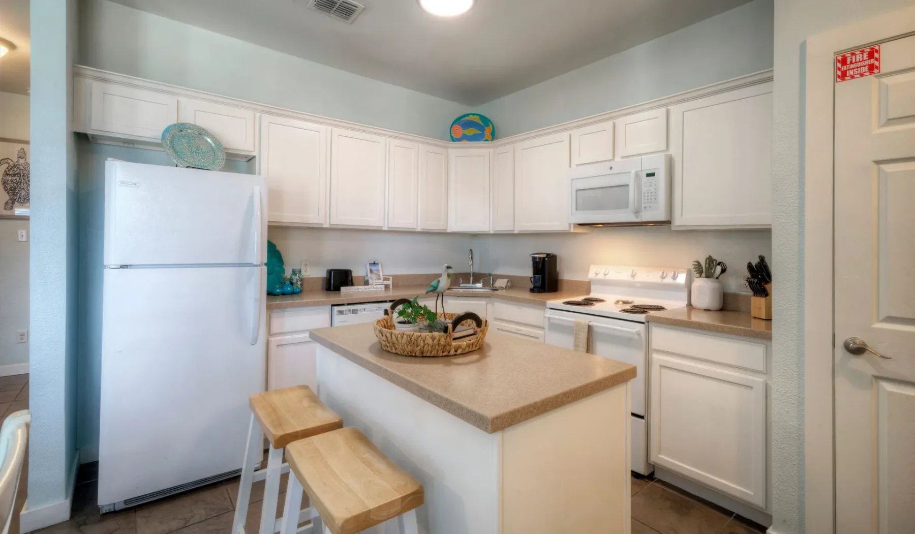 Una cocina luminosa con gabinetes blancos, electrodomésticos de acero inoxidable e isla central.