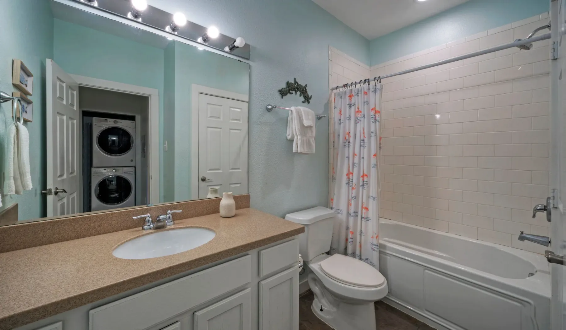 Un baño con lavabo, inodoro y bañera detrás de una cortina de ducha estampada.