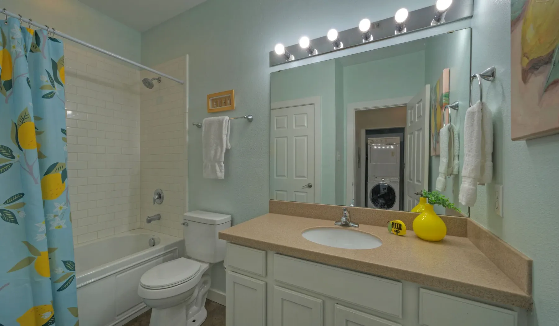 Un lavabo de baño con fregadero y una bañera detrás de una cortina estampada.