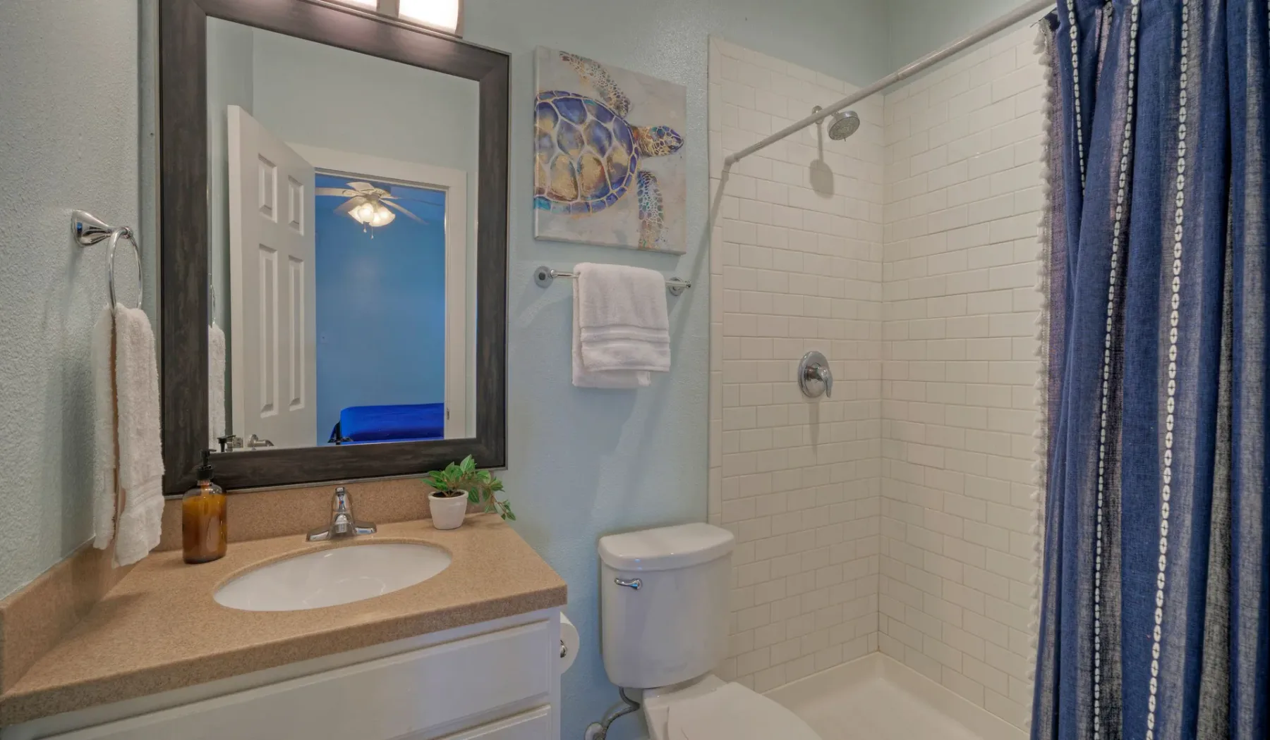 Un baño con lavabo, espejo, inodoro y ducha con azulejos.