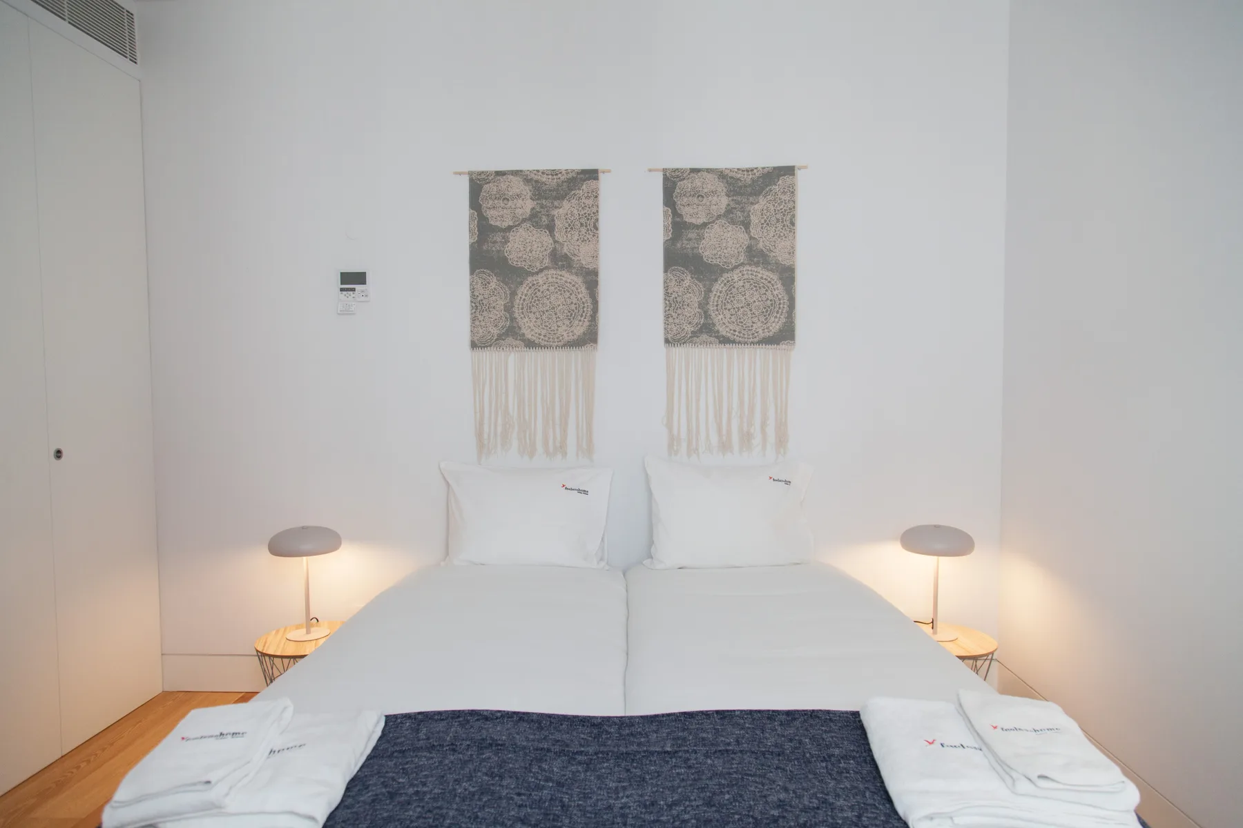Un dormitorio luminoso con una cama doble, mesillas y adornos en la pared.