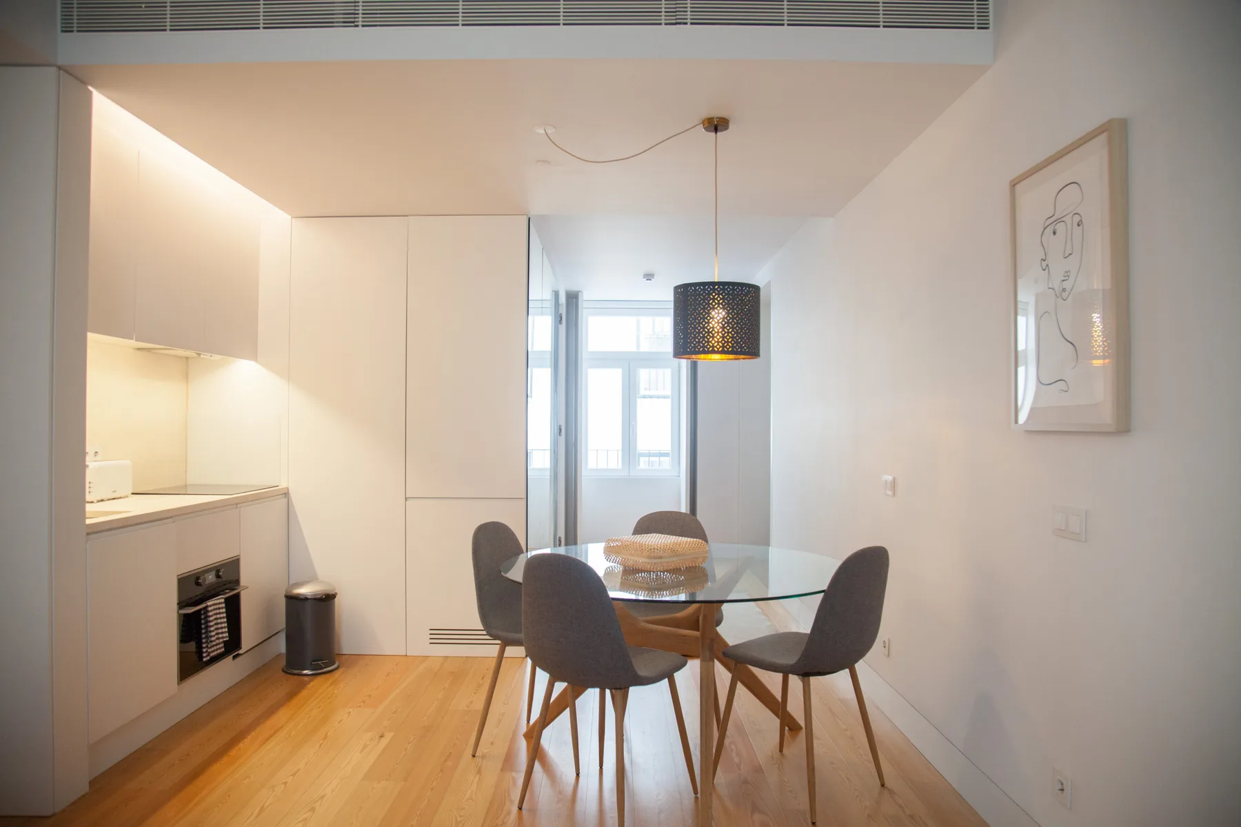 Un comedor luminoso con una mesa de cristal junto a una cocina compacta.