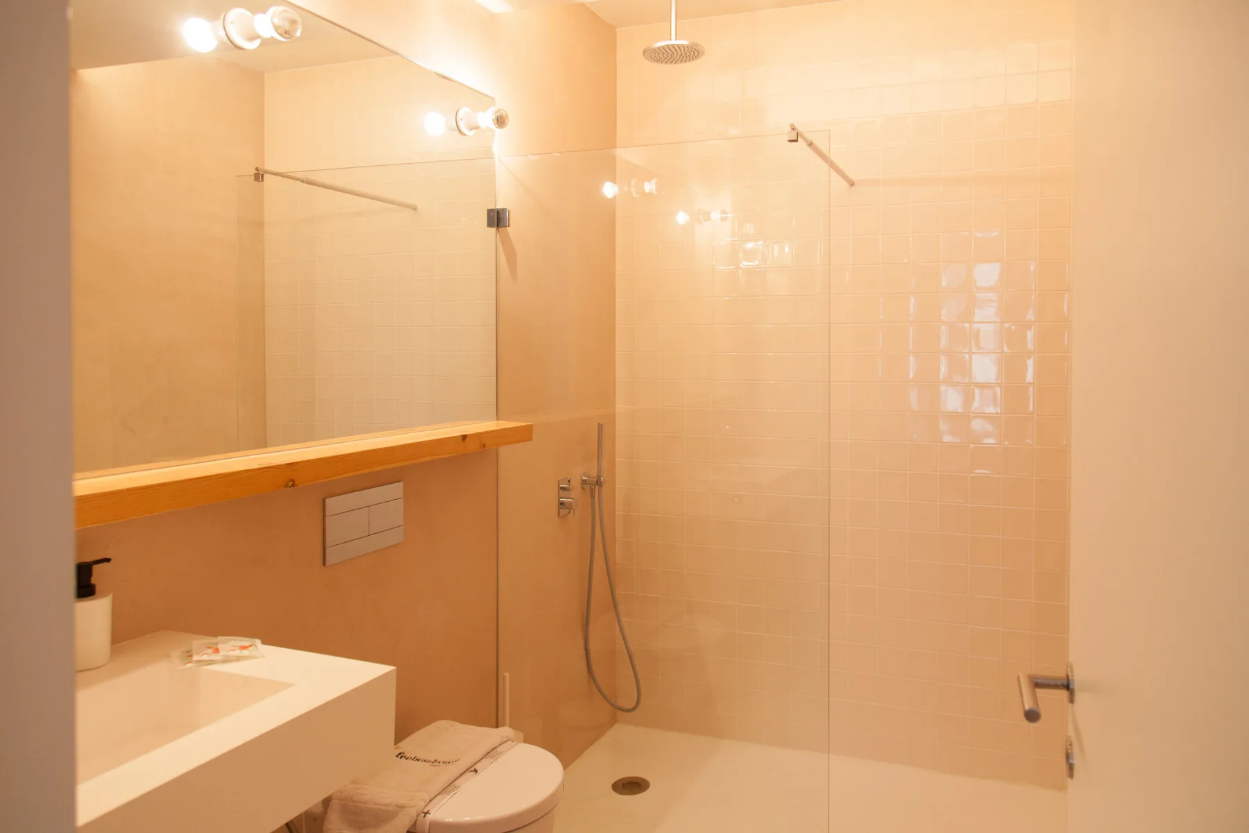 Un baño alicatado con lavabo, inodoro y mampara de ducha de cristal.