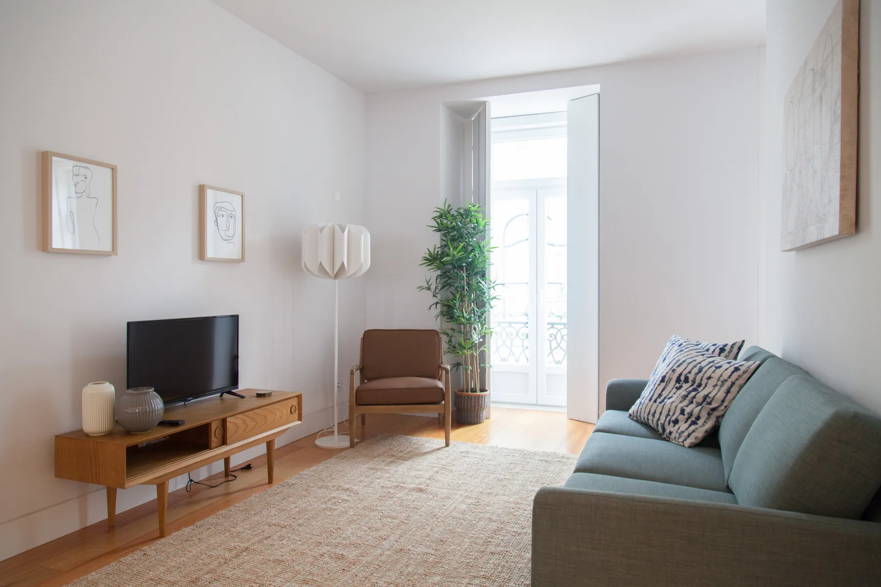 Una sala luminosa con asientos, un televisor y una ventana alta.