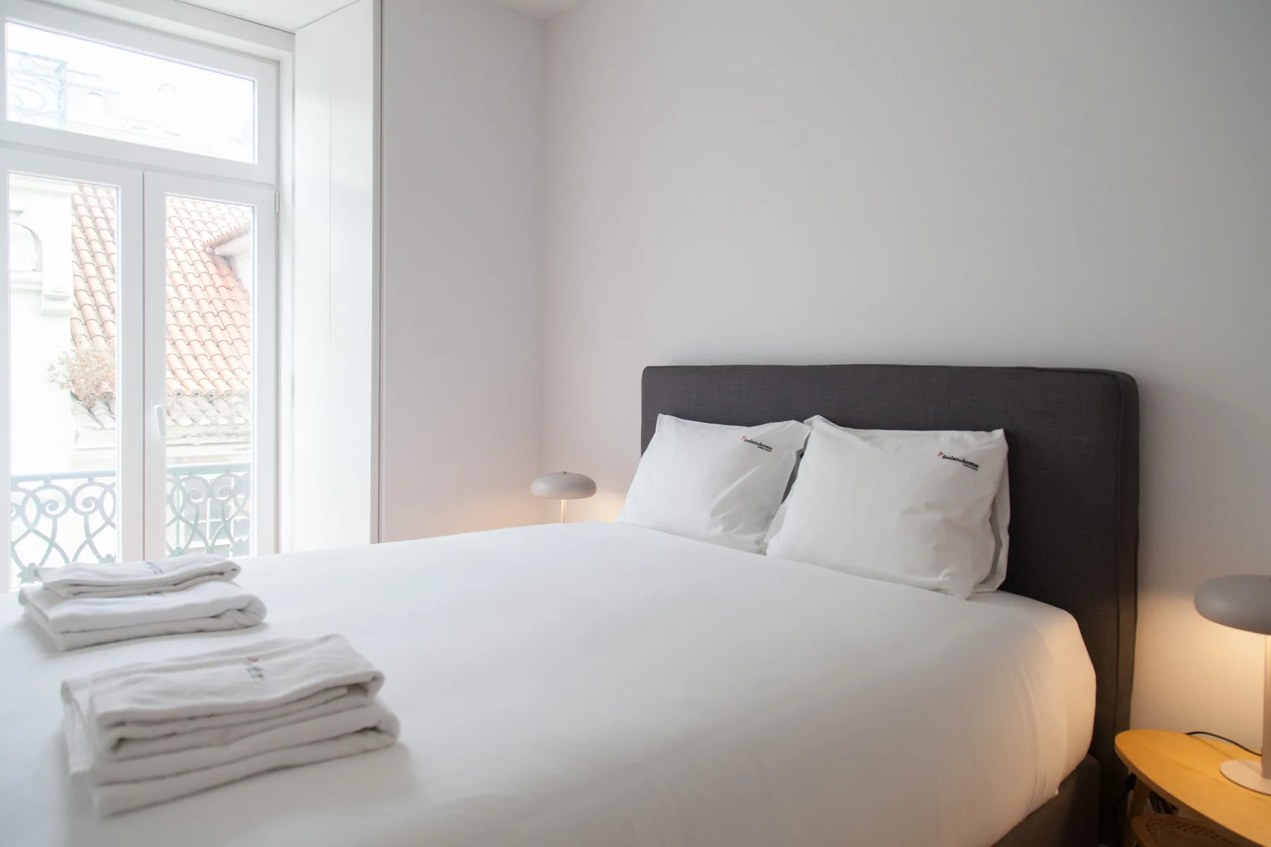 Un dormitorio luminoso con una cama tendida junto a una ventana grande.