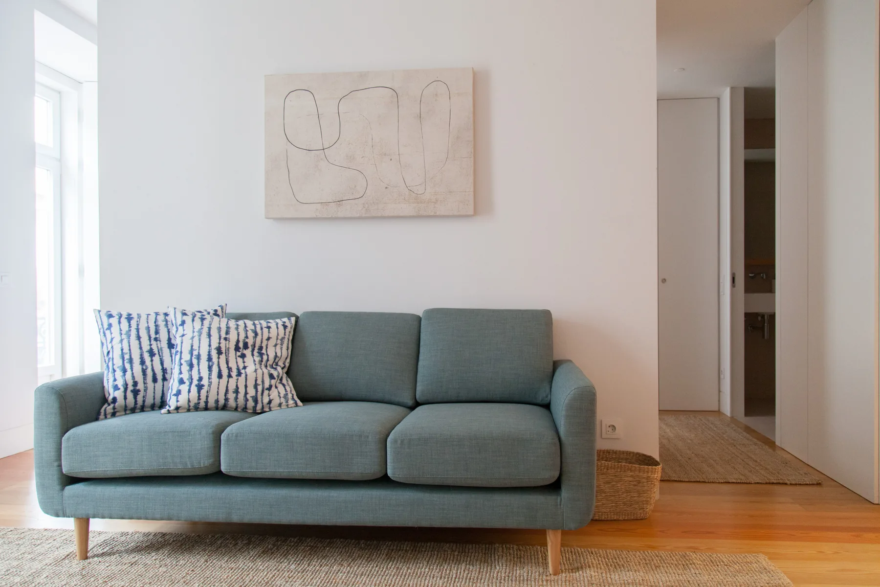 Una sala de estar con asientos azules, un cojín estampado y arte en la pared.