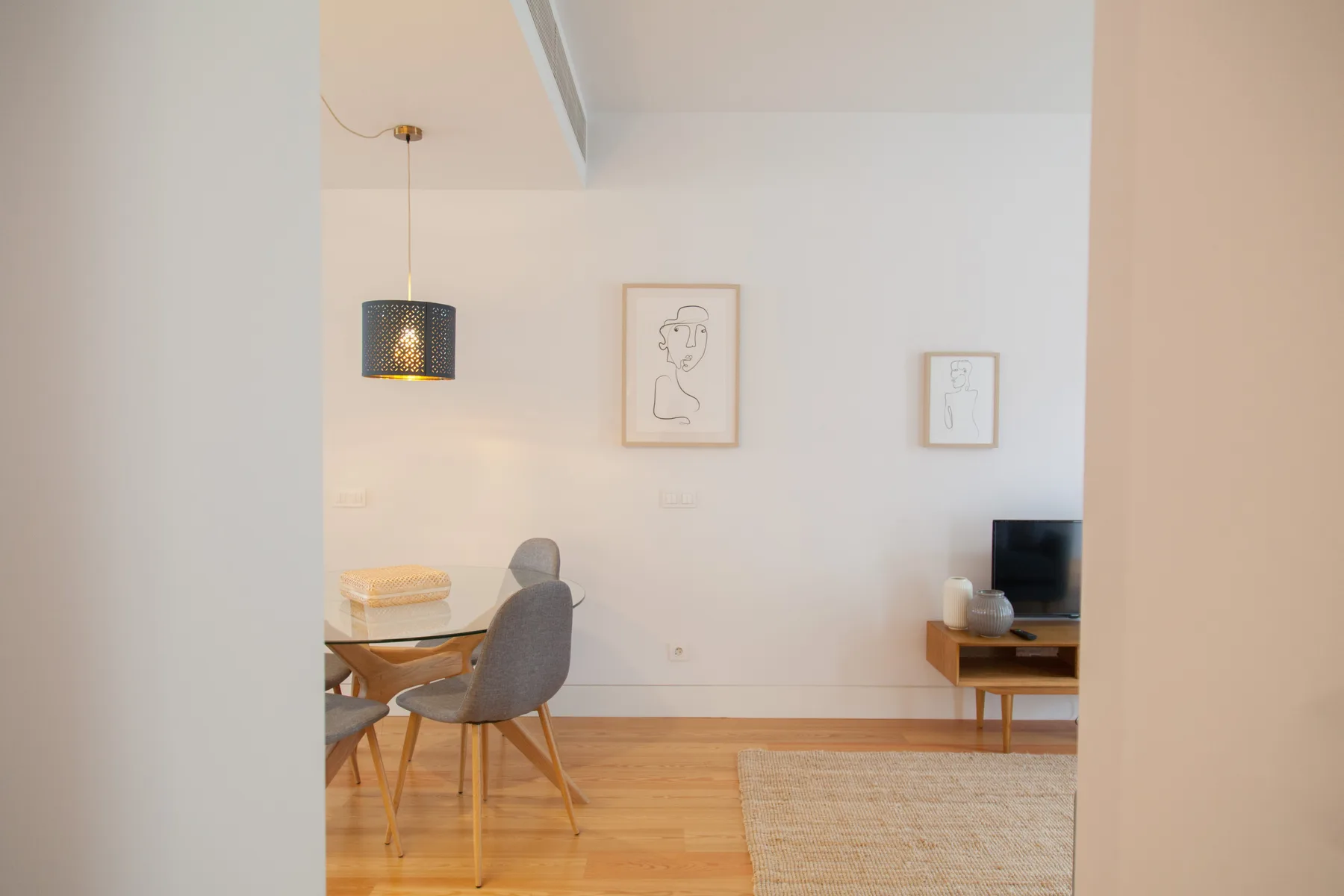 Una luminosa sala de estar y comedor con mesa, asientos y cuadros en la pared.