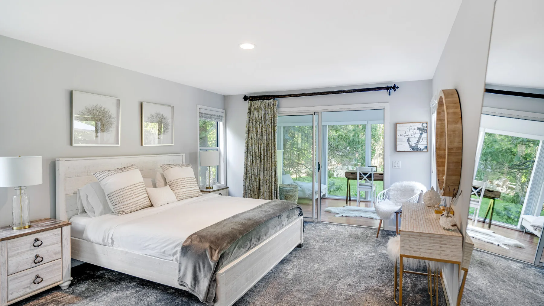 A bright bedroom with a large bed and sliding glass doors opening onto greenery.
