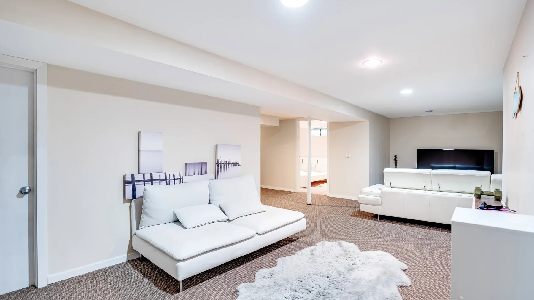 A bright living area with white seating and a light rug.