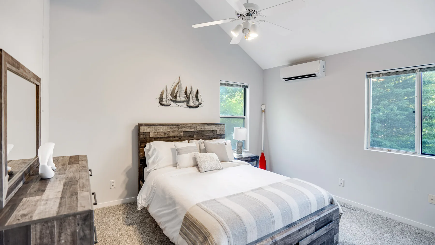 A bright bedroom with a large bed and windows overlooking greenery.