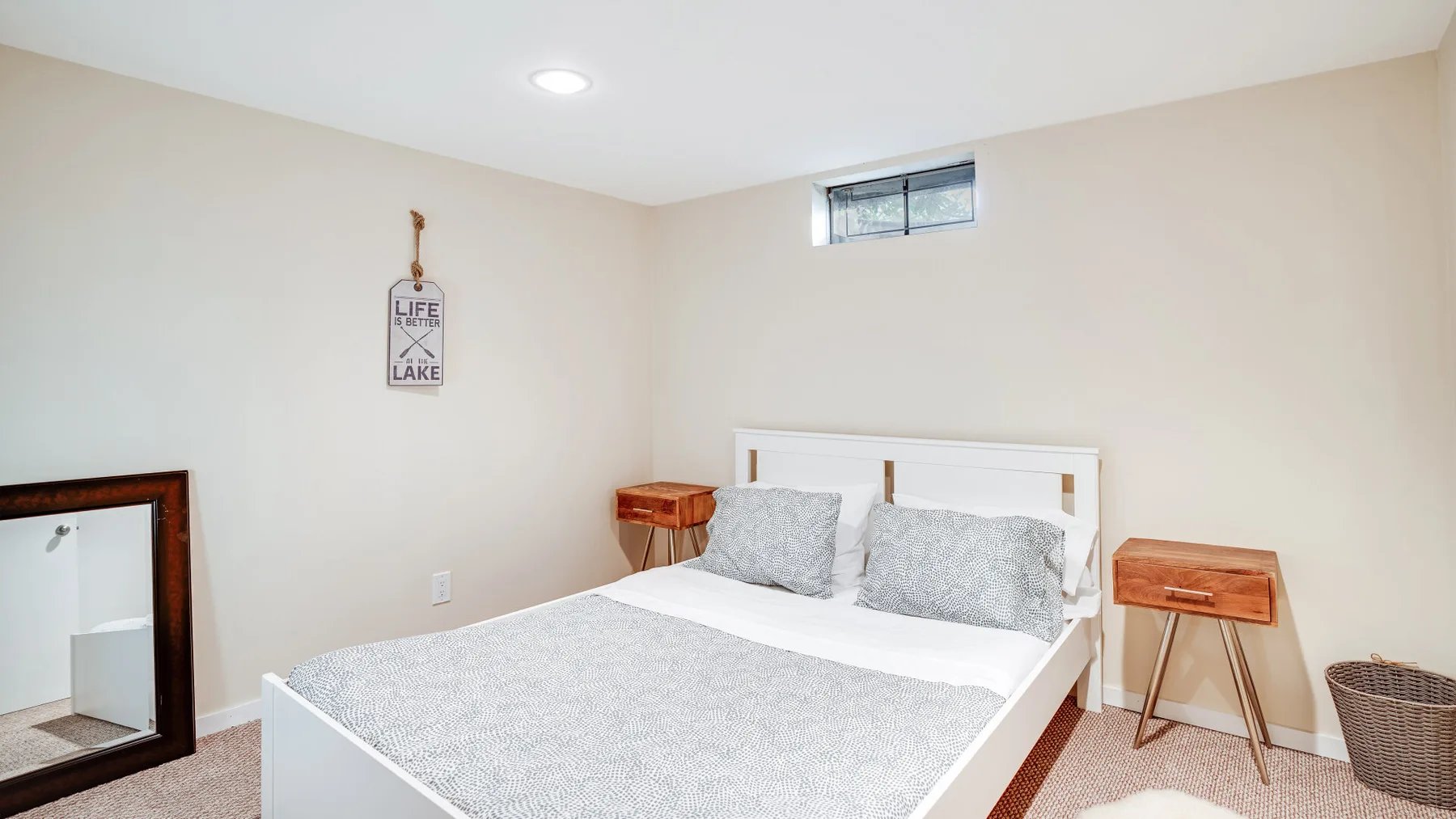 A bedroom with a bed dressed in light gray bedding and small bedside tables.