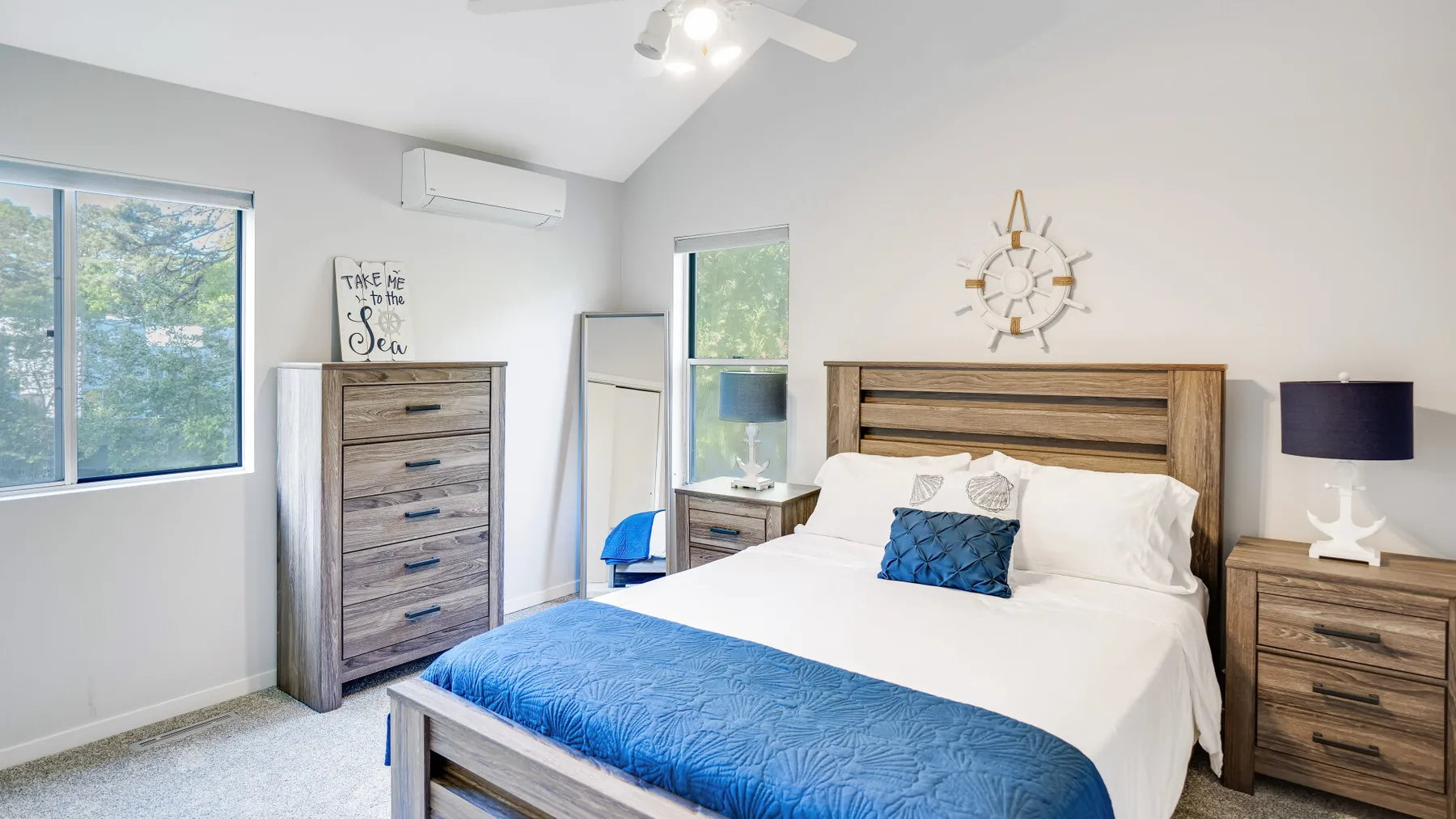 A bright bedroom features a bed with white bedding and a blue cover.