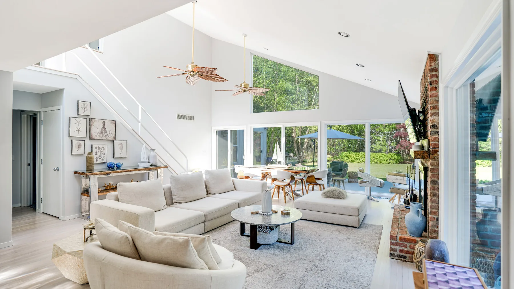 A bright living room with a sectional seating area and large windows overlooking greenery.