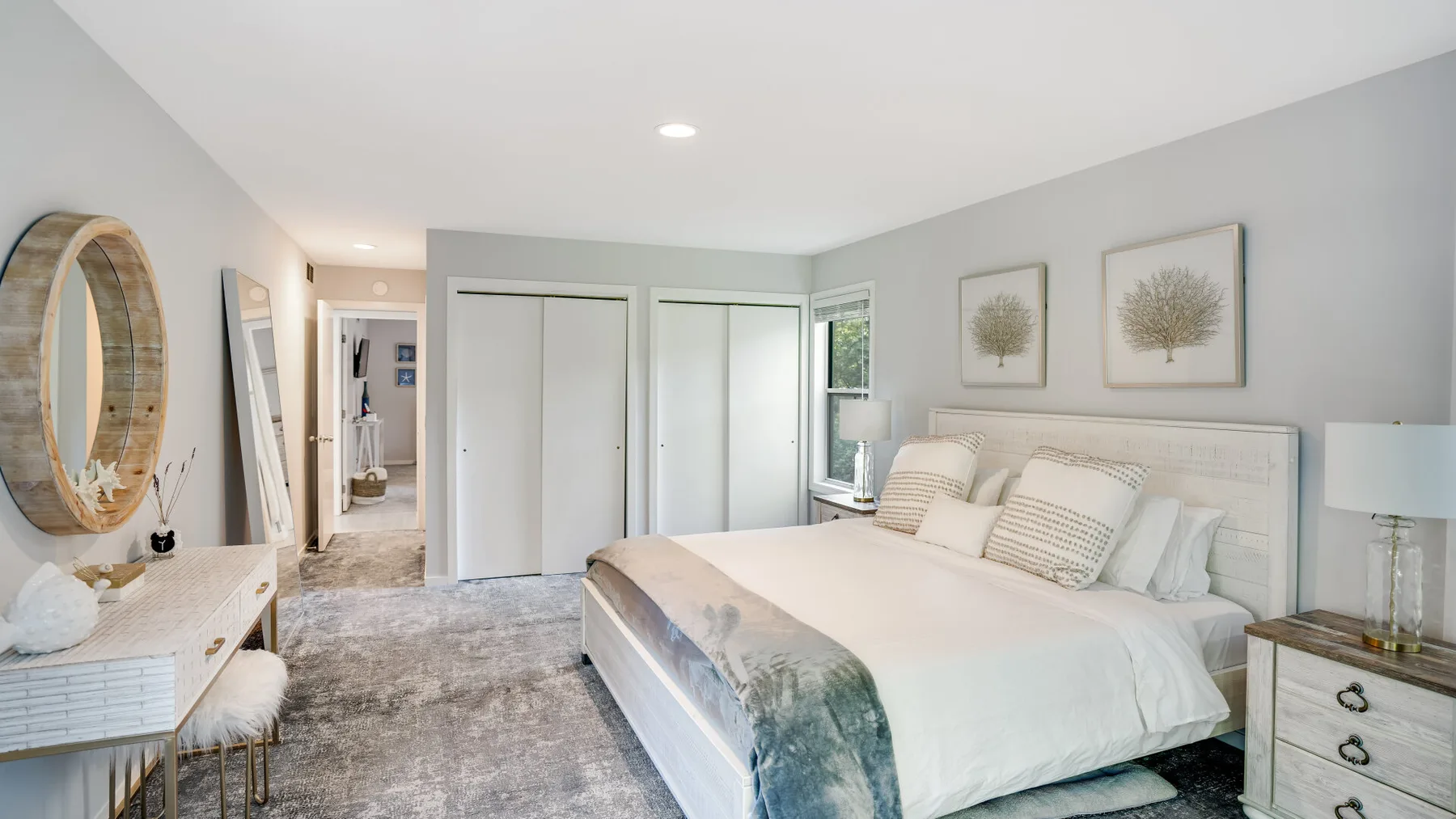 A bright bedroom with a large bed, bedside tables, and wall art.