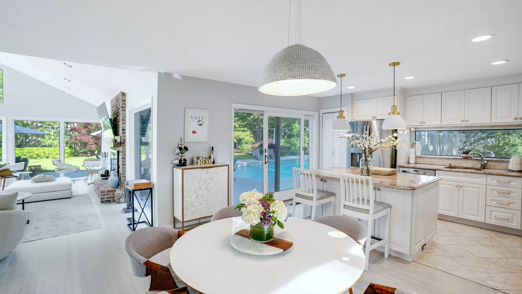 A bright open-plan kitchen and dining area overlooks a pool through large glass doors.