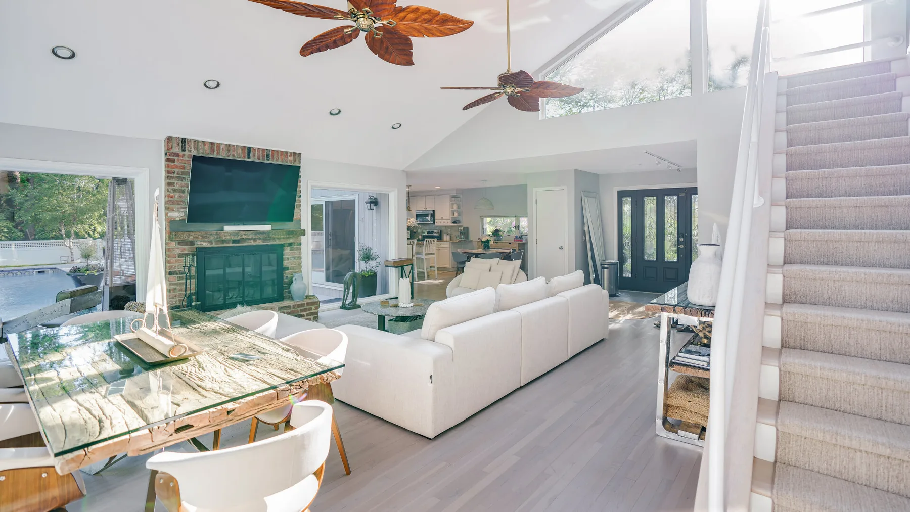 A bright living room with a dining table, seating, and a staircase.