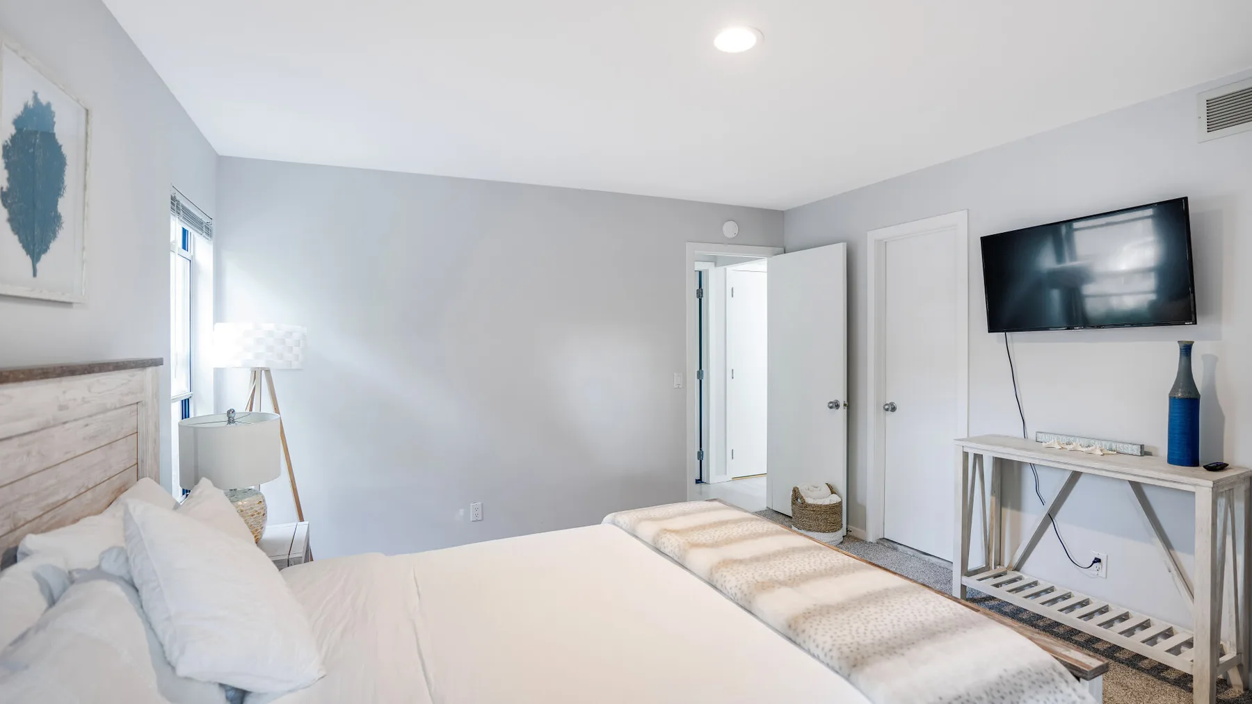 A bedroom with a bed, a television, and an open doorway.