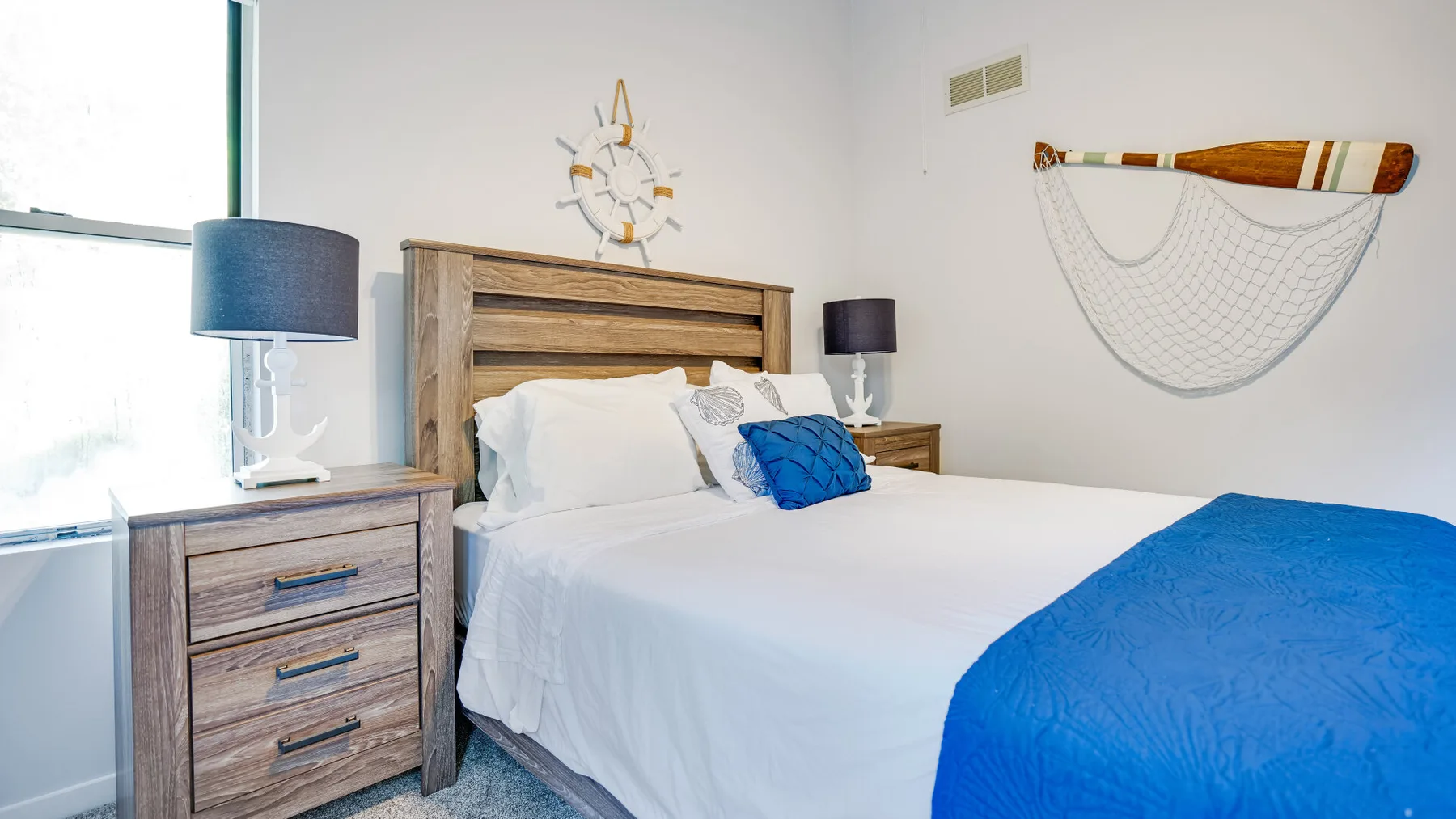 A bright bedroom with a neatly made bed and blue bedding.