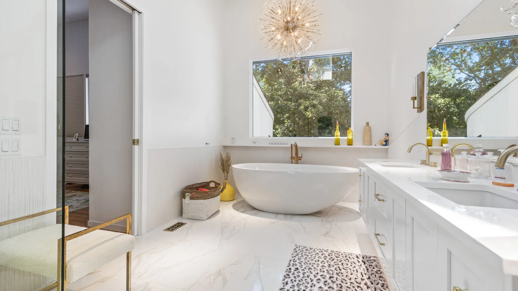 A bright bathroom features a freestanding bathtub and a long vanity.