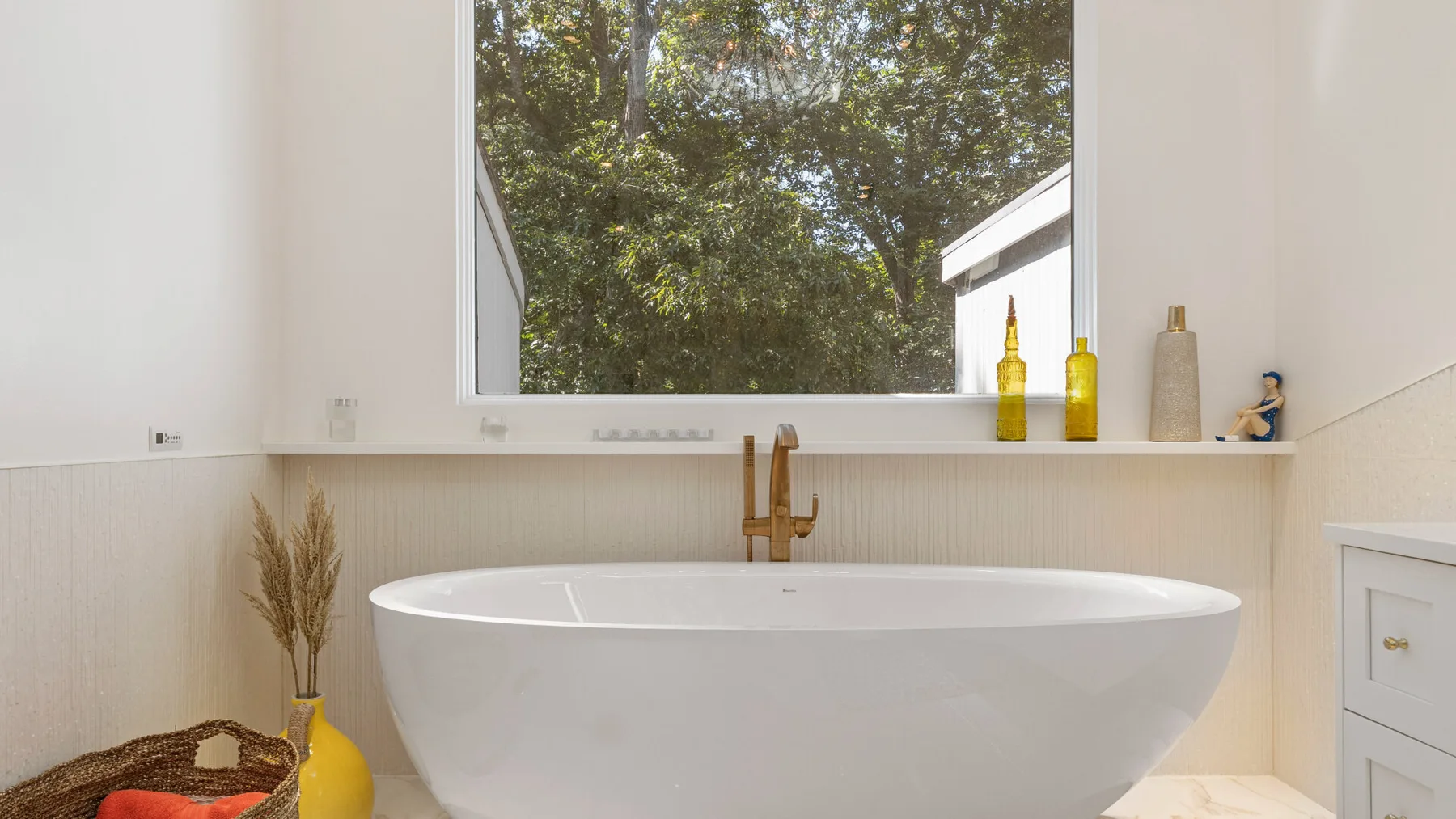 A bathroom with a freestanding bathtub beneath a large window.