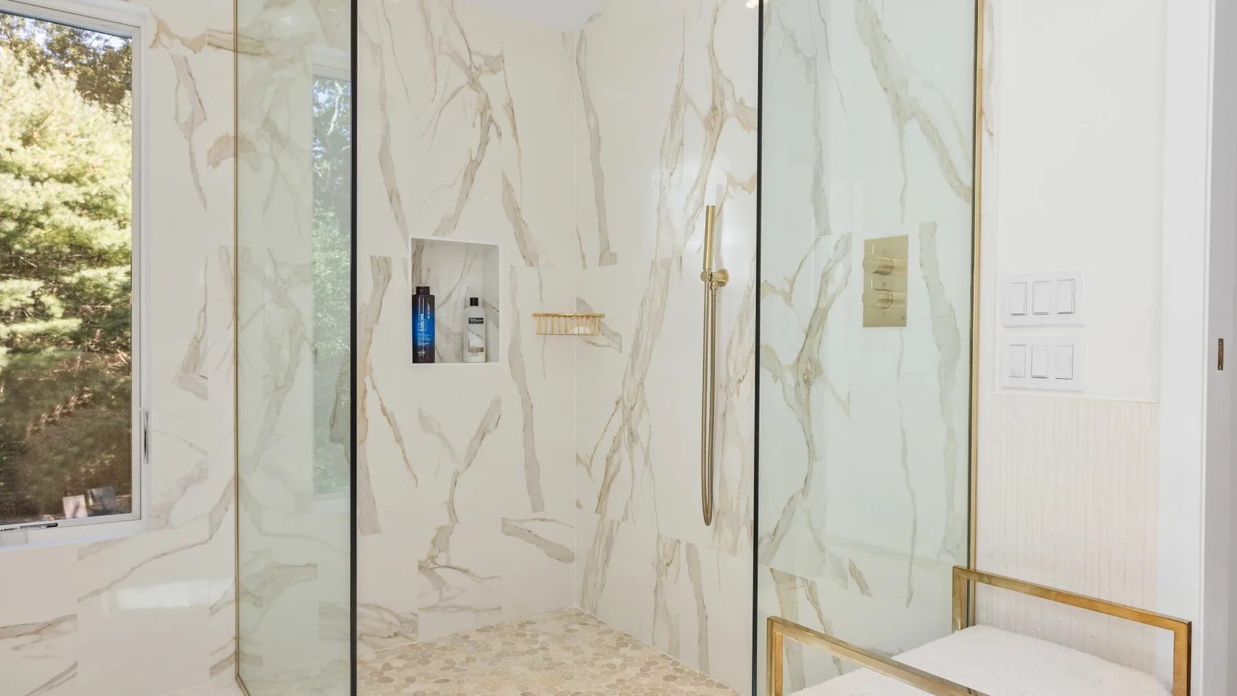 A bright bathroom with a glass shower and a white vanity area.