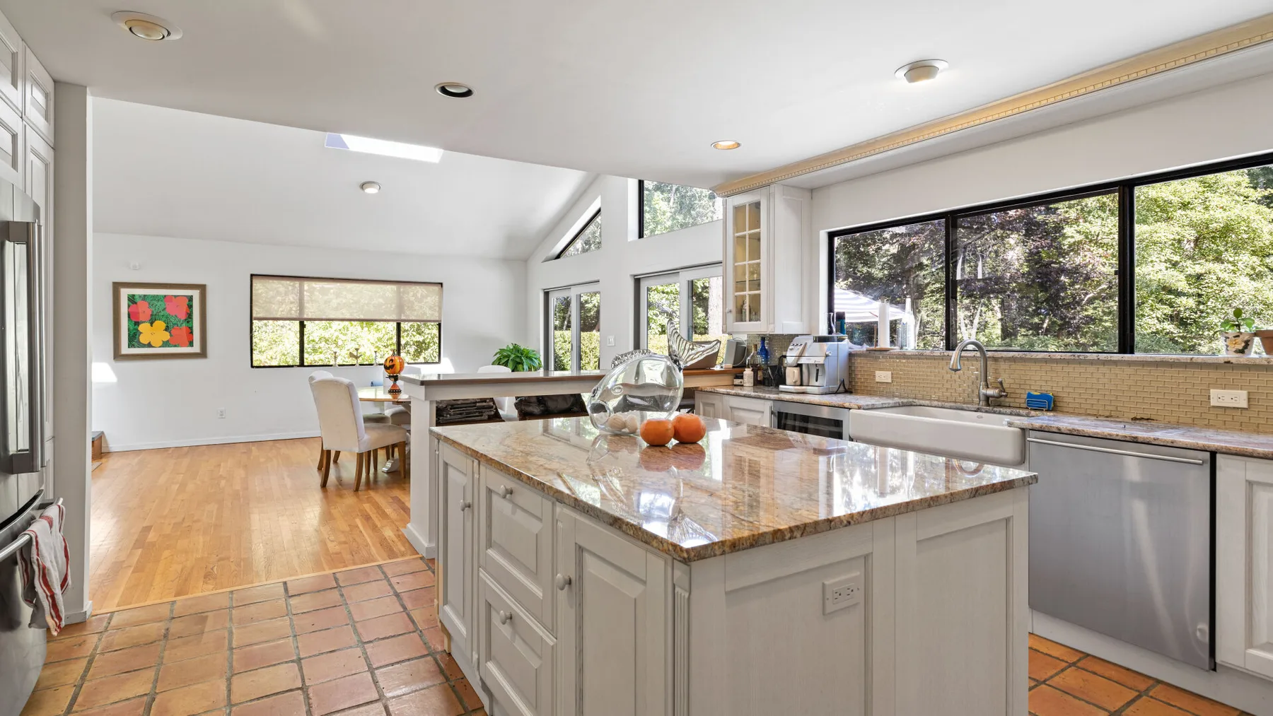A bright kitchen with a central island and large windows overlooking trees.