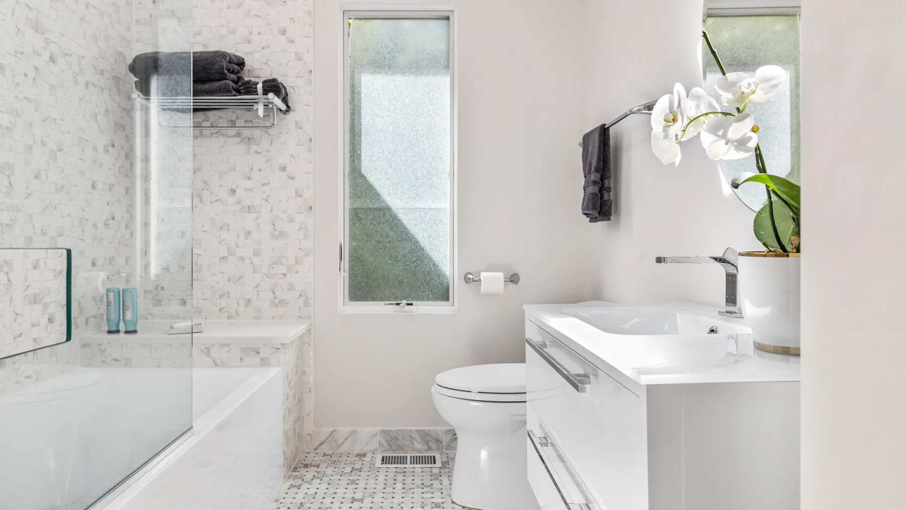 A bright bathroom with a bathtub, shower, and white vanity.