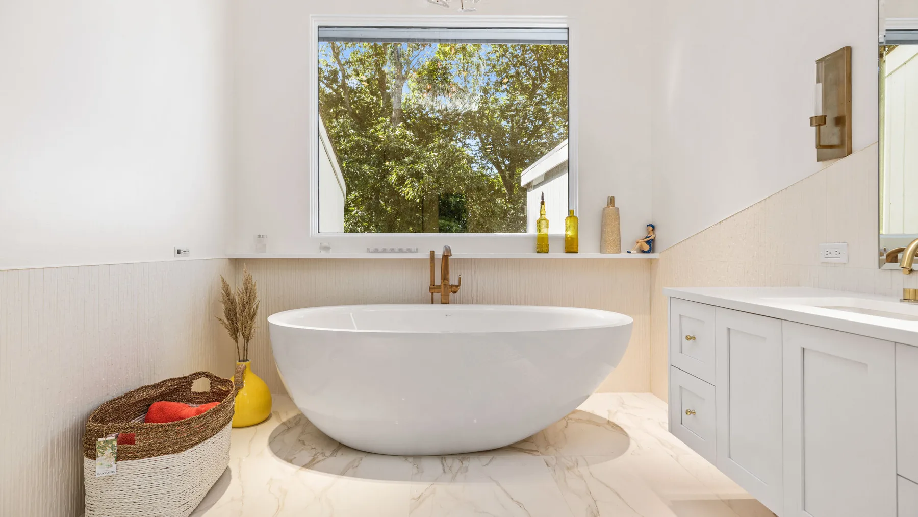 A bright bathroom with a freestanding bathtub beneath a window.