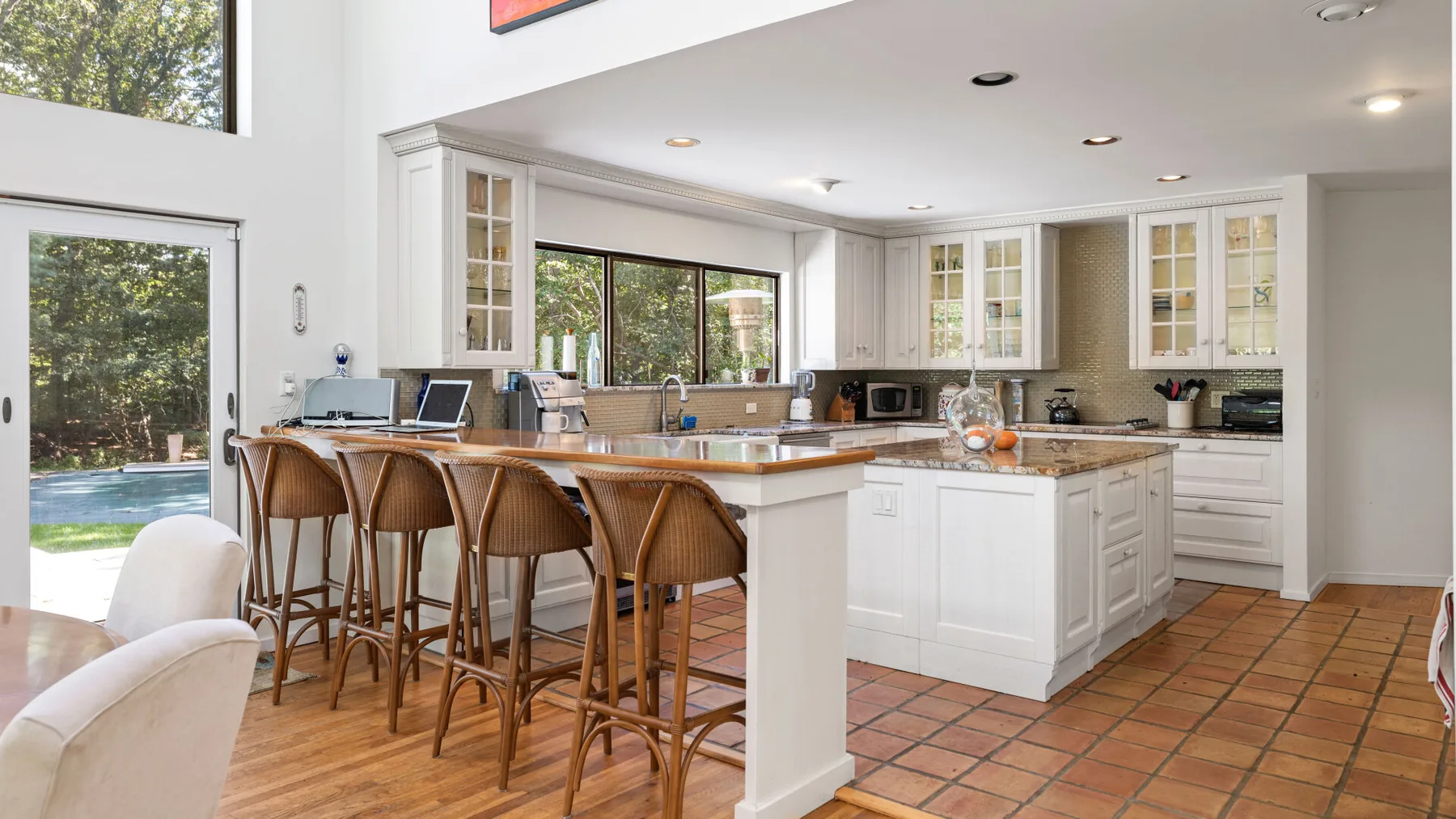 A bright kitchen with a central island, bar seating, and large windows.