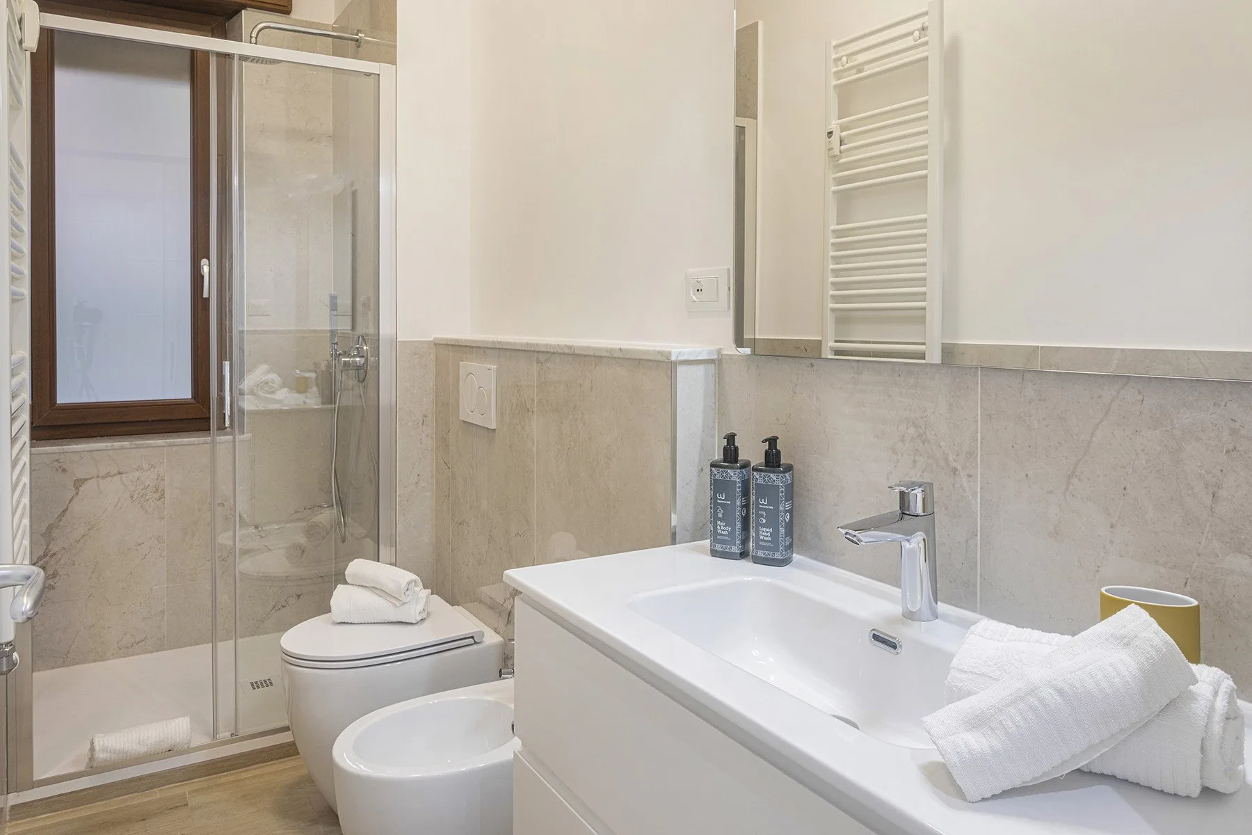 A bright bathroom with a glass shower, bathtub, and sink.