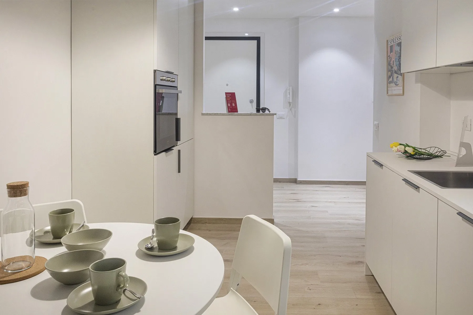 A bright kitchen and dining area with a round table set with dishes.