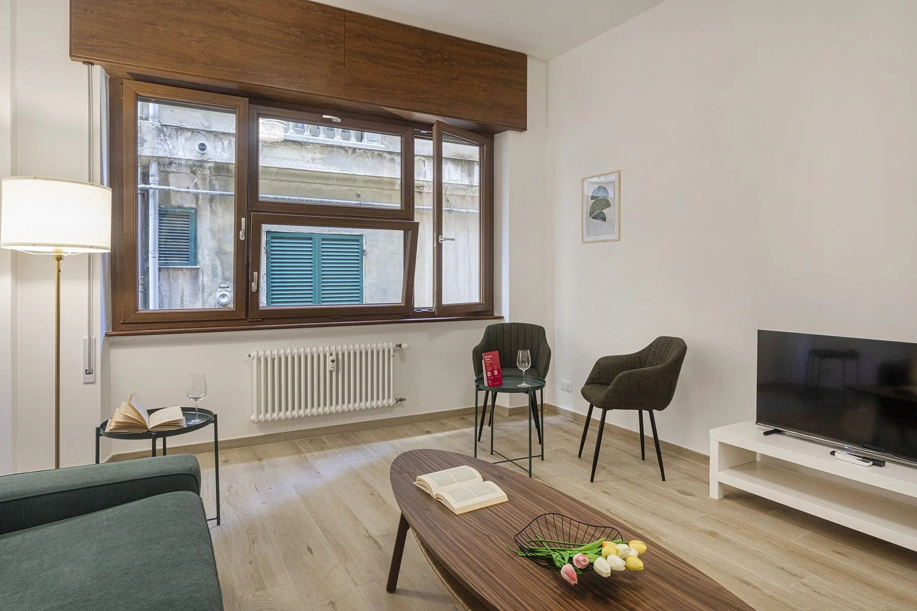 A living room with a large window, seating, and a television.