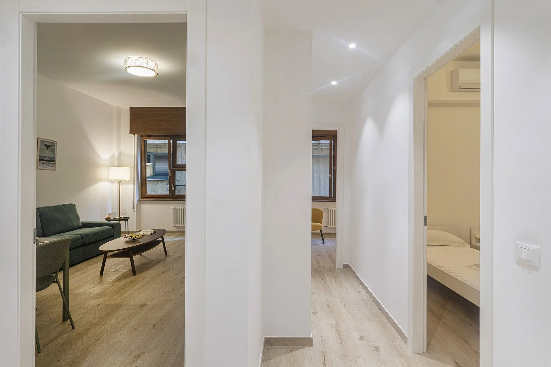 A bright hallway connects a living area with a bedroom.