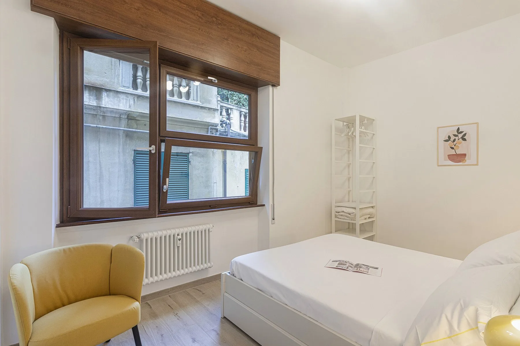 A bedroom with a bed, a yellow chair, and a large window.
