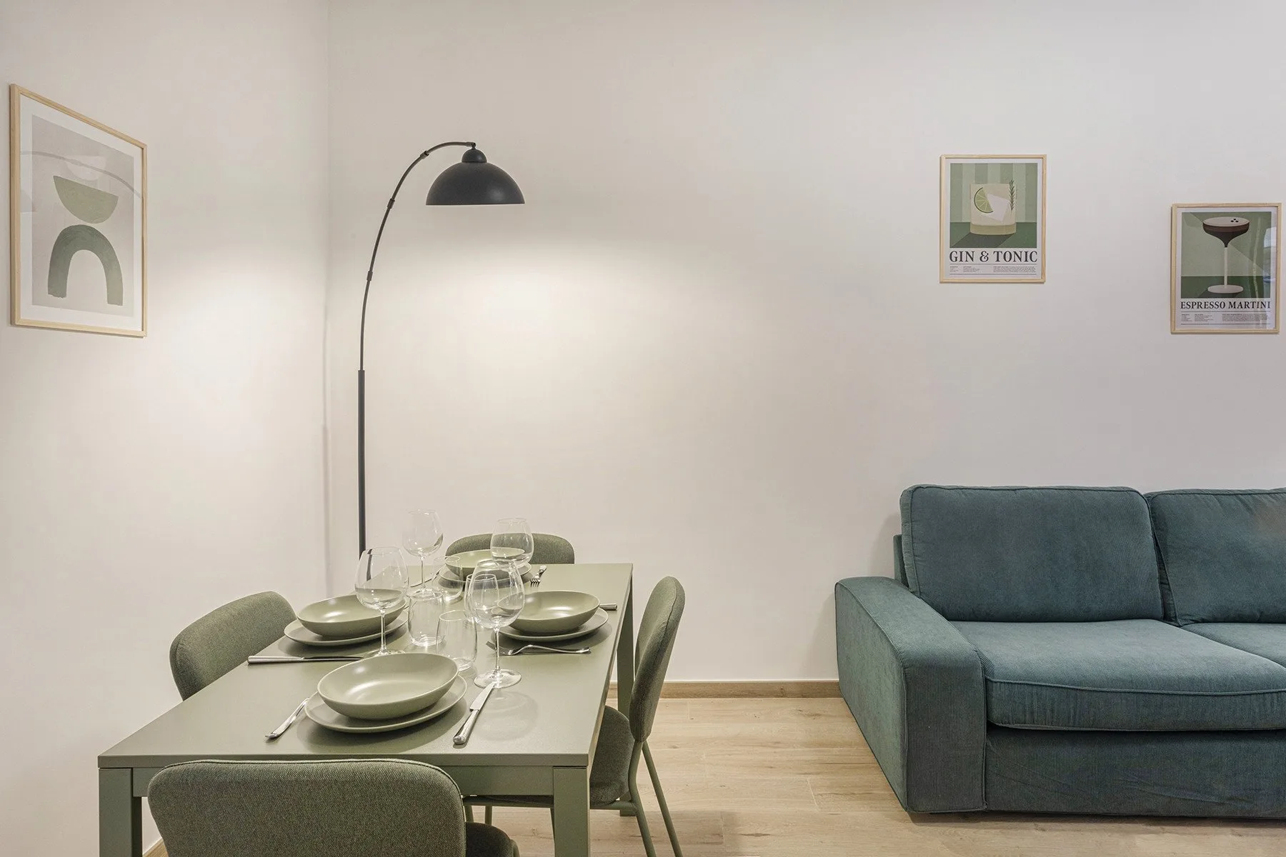 A dining area with a set table beside a teal sofa.
