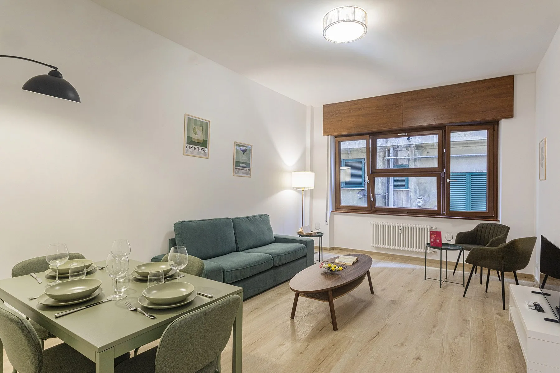 A living and dining area with a teal sofa and a table set for a meal.