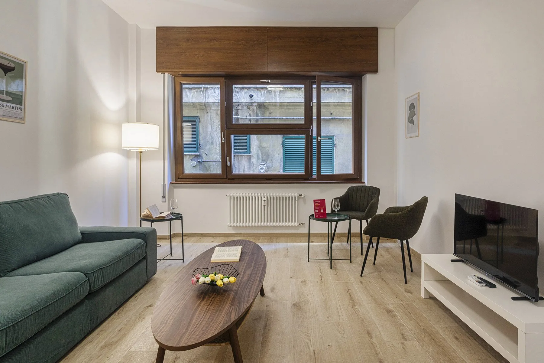 A living room with seating, a coffee table, and a television by the window.