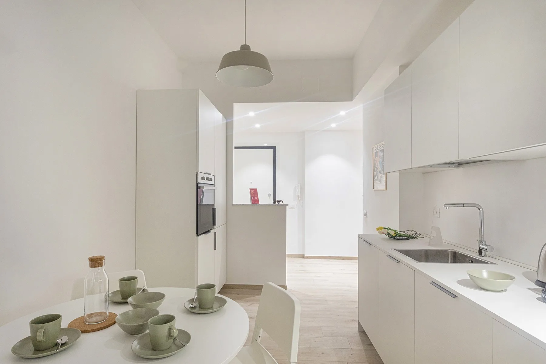 A bright modern kitchen with a dining table and a long countertop.