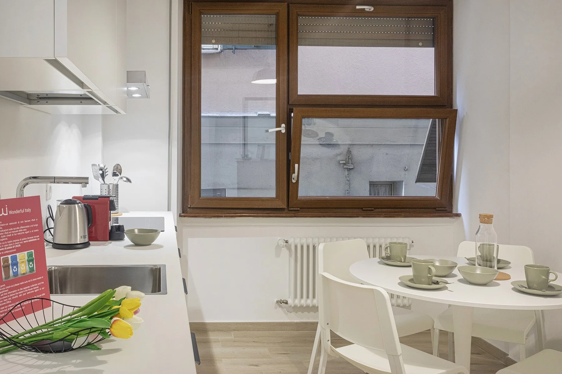 A bright kitchen and dining area with a table set beside a large window.