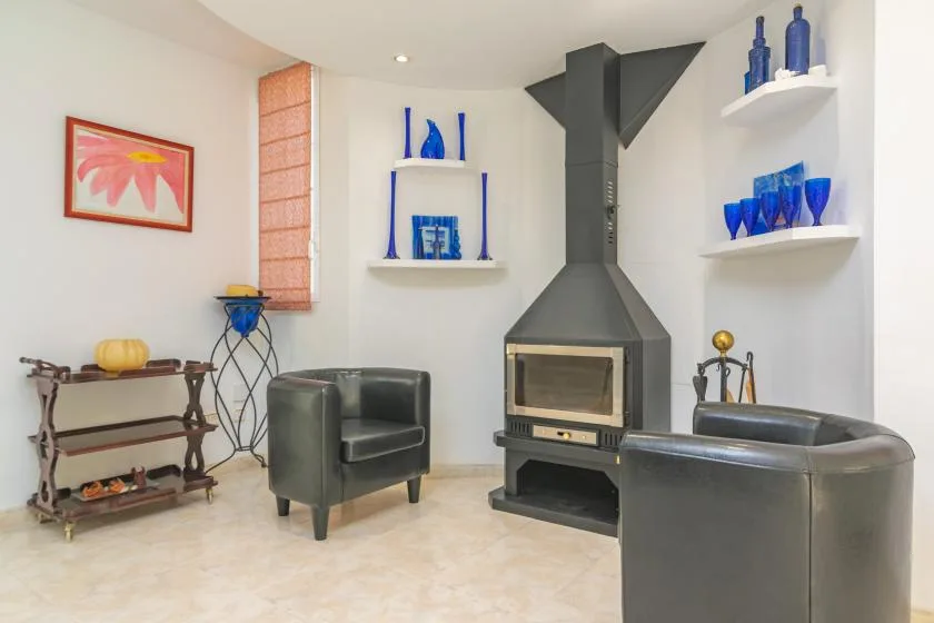 Una sala de estar con chimenea, asientos oscuros y adornos de vidrio azul en estantes.